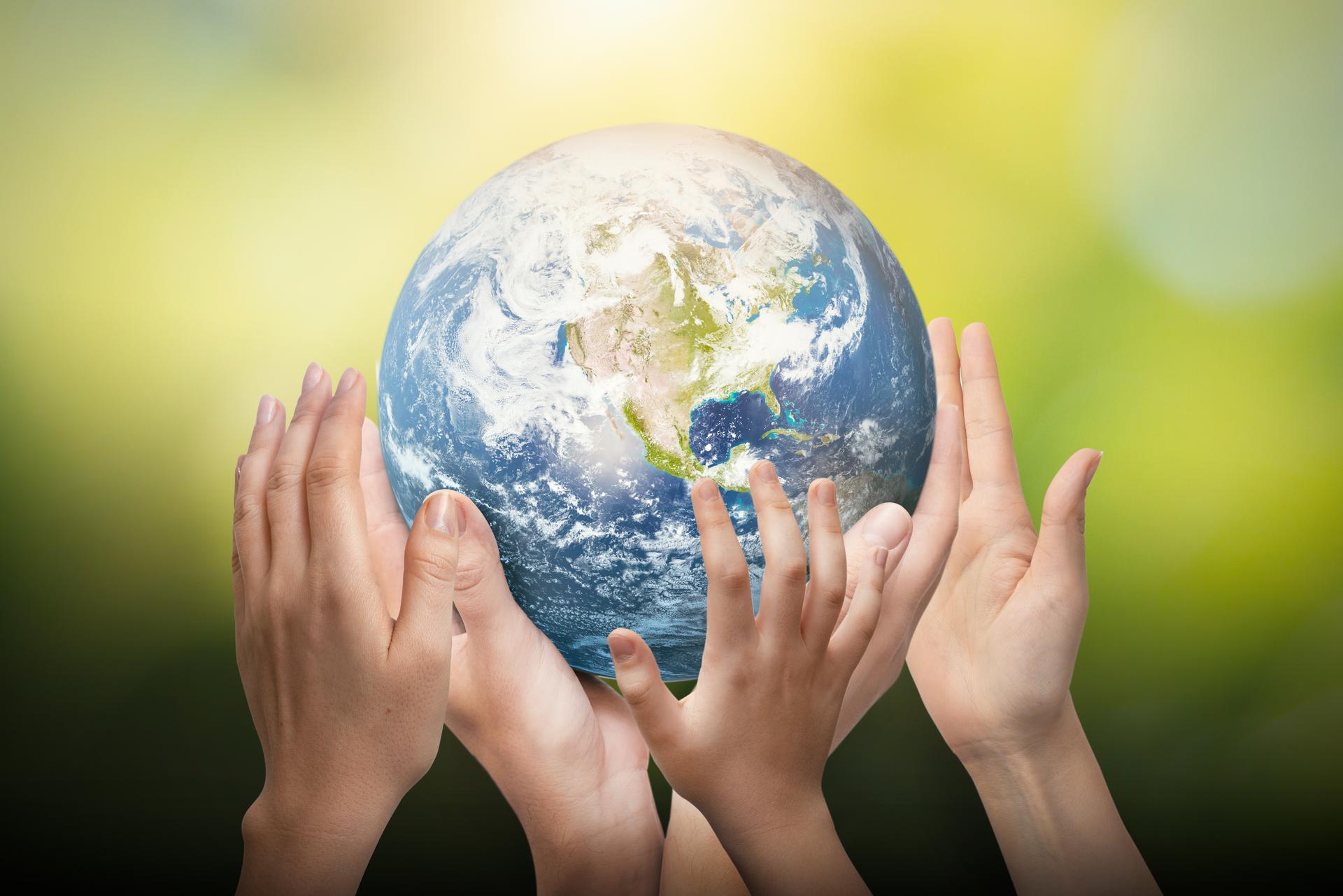 Earth with green background and caring hands around the earth