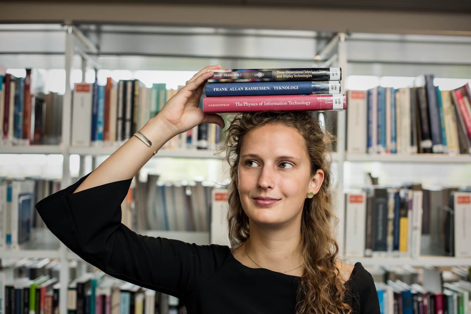 Female student balancing a stack of books on her head
